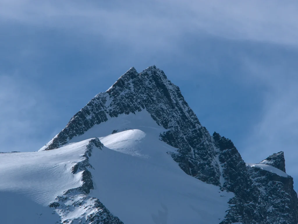 Großglockner teilweise schneebedeckt mit blauem Himmel im Hintergrund. Foto von Benjamin Sadjak-Unsplash