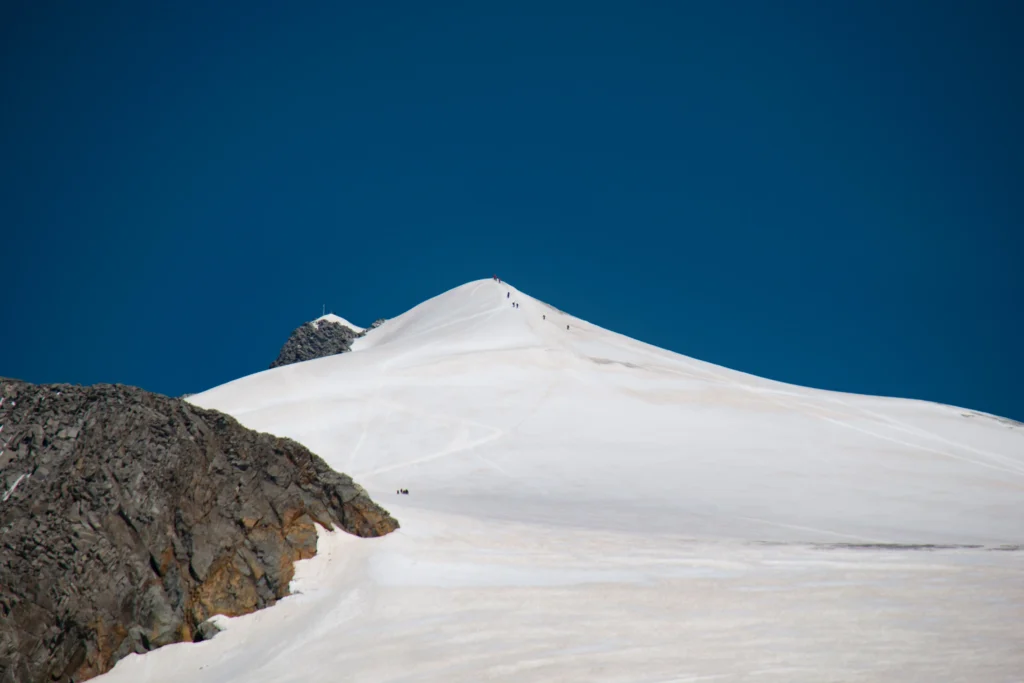 Schneebedeckter Großvenediger mit blauem Himmel im Hintergrund. Foto von Tim Dennert-Unsplash