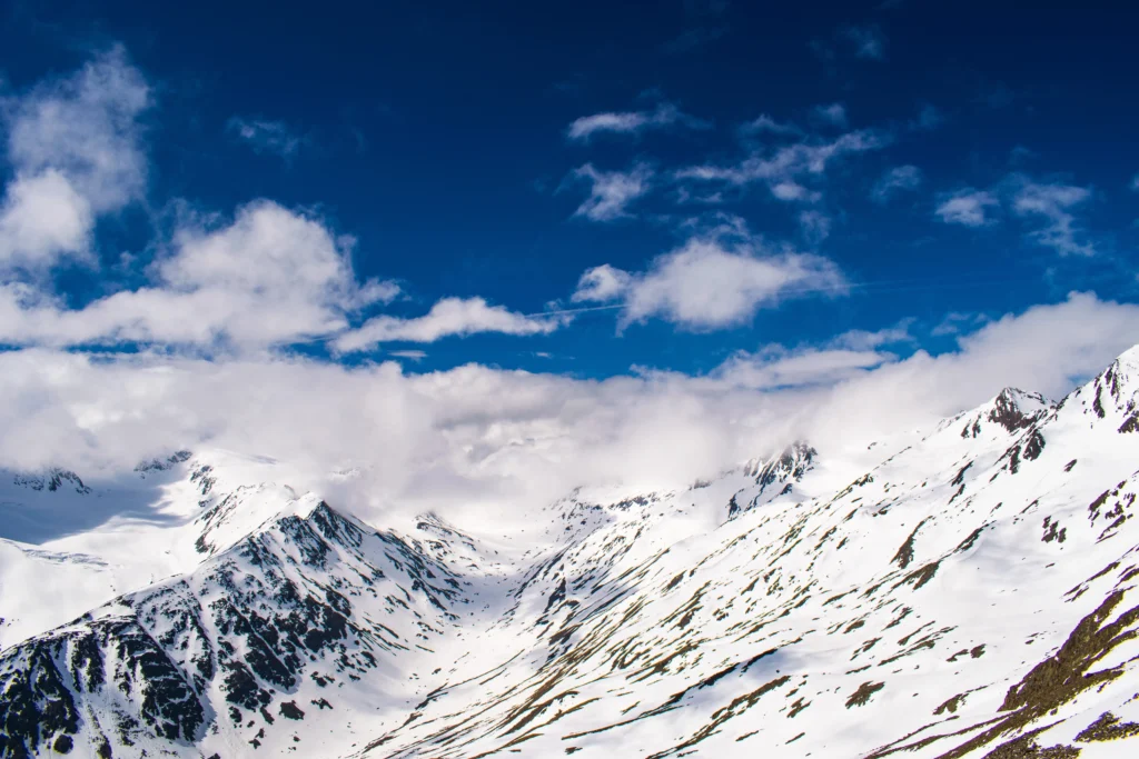 Schneebedeckte Ötztaler Alpen mit teilweise blauem Himmel und Wolken im Hintergrund. Foto von Michal Pech-Unsplash