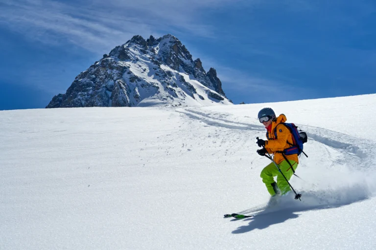 Skitourenfahrer bei der Abfahrt mit Berg und blauem Himmel im Hintergrund. Foto von Cyprien Delaporte-Unsplash