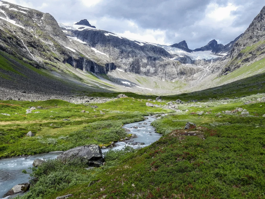 Nationalpark Jotunheimen mit Bach, Berge, Gletscher und Wolken im Hintergrund. Foto von Matej Drha-Unsplash