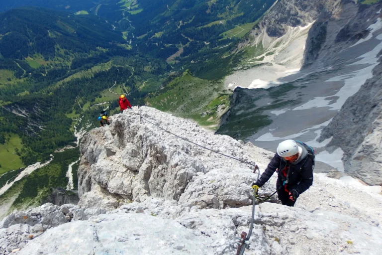 Klettersteiggruppe am Drahtseil mit Berge und grüner Landschaft im Hintergrund. Foto von Maja Kochanowska-Unsplash