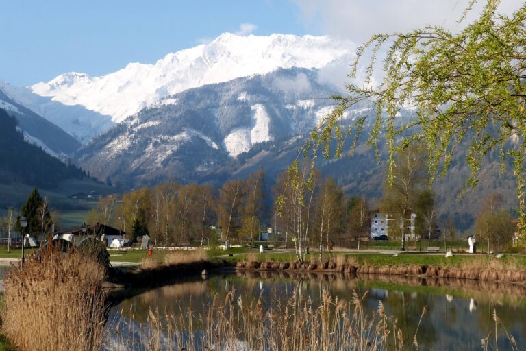 Auf dem Bild sieht man einen See. Im Hintergrund befinden sich zwei hohe Berge. Eins von diesem Gipfel ist mit Schnell bedeckt. Das Wetter ist gut. Die Sonne scheint