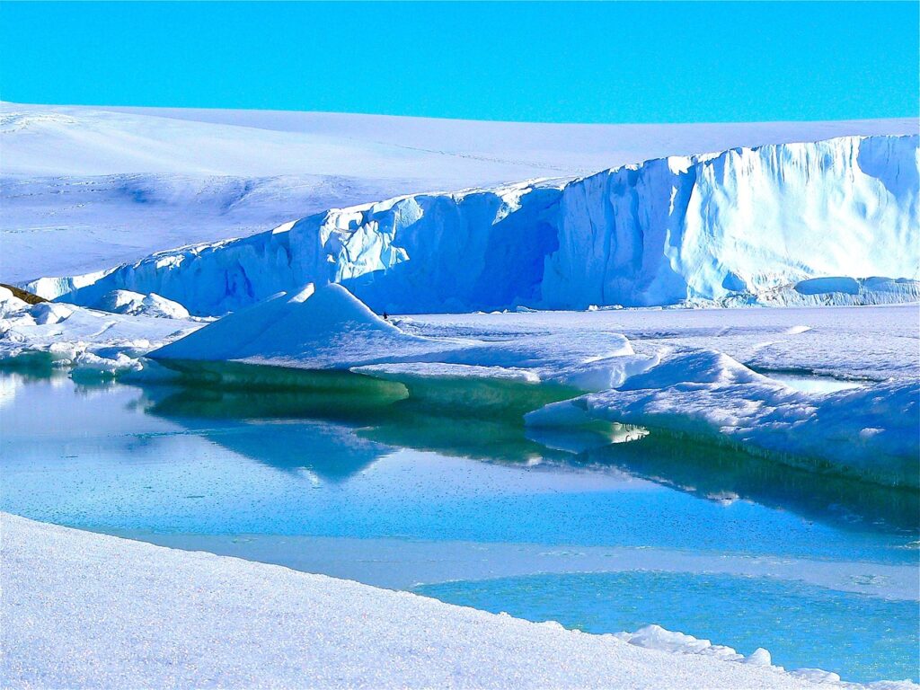 Auf dem Foto ist ein Eisberg zu sehen. Es ist einer von Seven Summits. Überall sieht man Eis. Das Wetter ist gut. Die Sonne scheint.