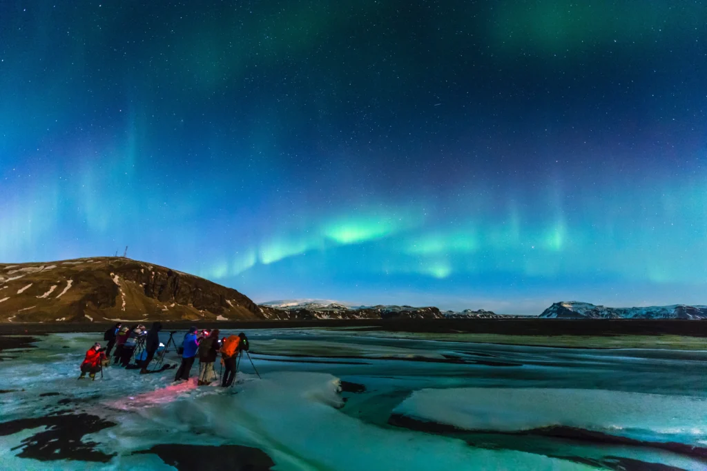 Menschen beobachten und fotografieren grünes Nordlicht. Foto von Ken Cheung-Unsplash